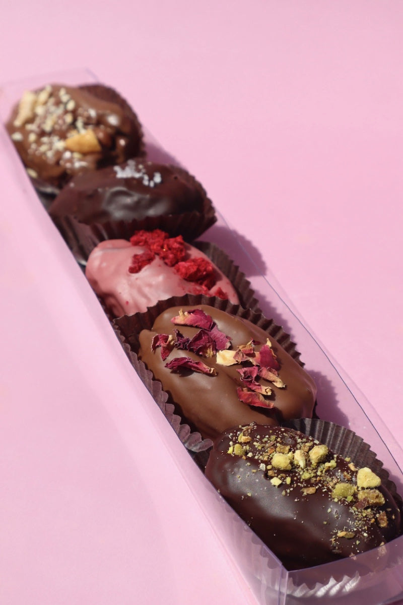 Assorted chocolate-covered dates by Firdaus Chocolate, featuring glossy chocolate coatings on ripe, sweet dates.