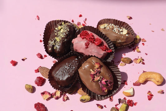 Assorted Firdaus Chocolate covered dates with glossy chocolate coating and chewy date interior on a white background.